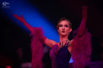 Dancesport competitor: Female dancer: deep purple Latin dress with voluminous feather-like sleeves and 