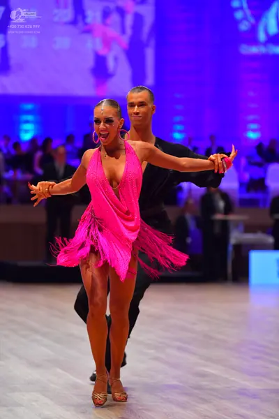 Dancesport competitor: Female dancer: bright pink latin dress with fringe