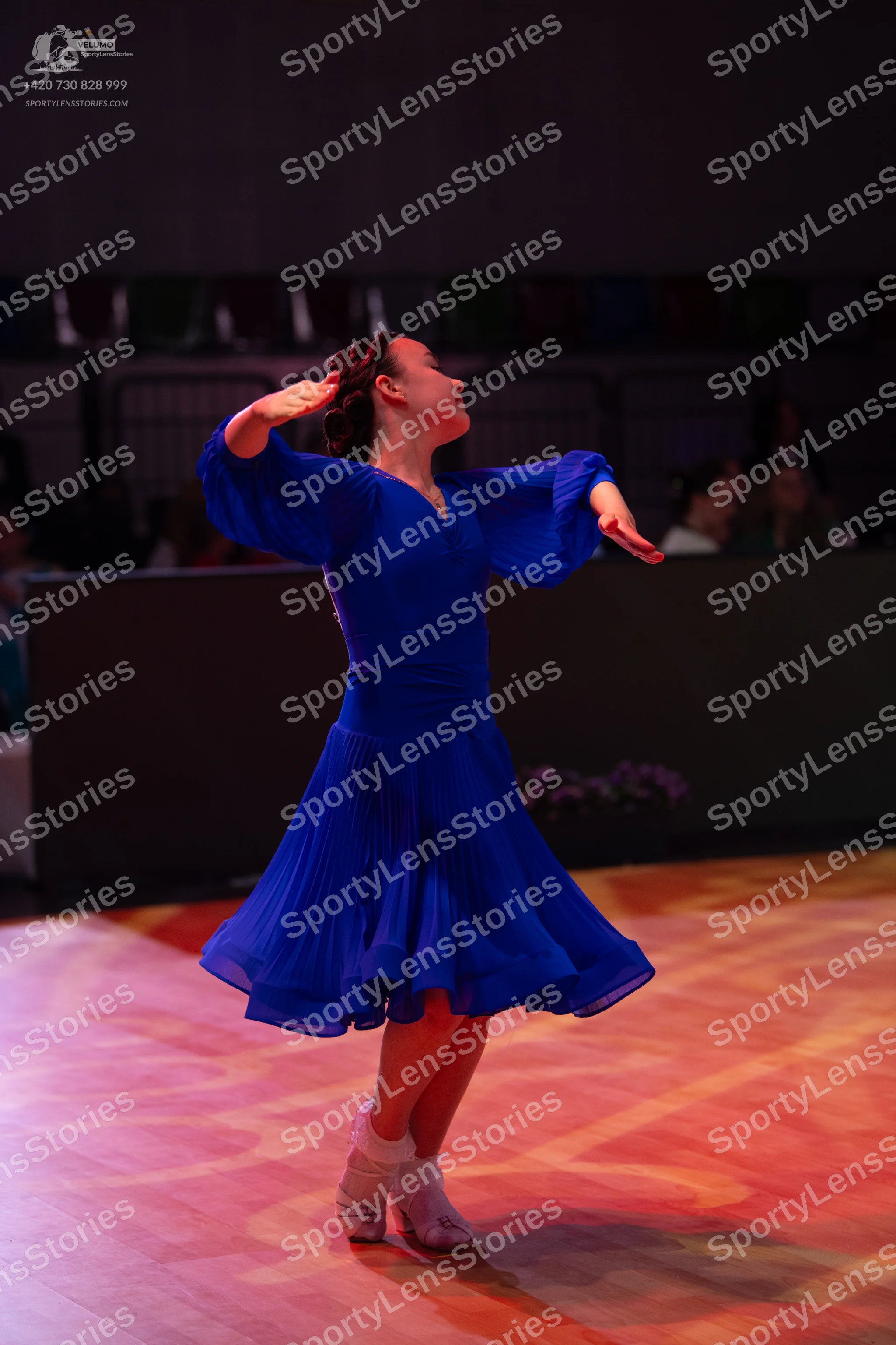 Dancesport competitor: Female dancer: royal blue ballroom dress with long, flowing sleeves and a flared