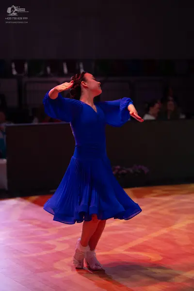 Dancesport competitor: Female dancer: royal blue ballroom dress with long, flowing sleeves and a flared