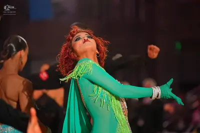 Dancesport competitor: Main female dancer: bright green long-sleeved latin dress with fringe and sequin