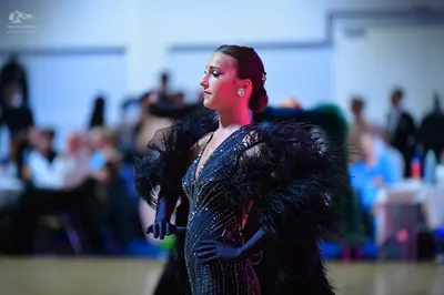 Dancesport competitor: Female dancer: black sequined dress with a deep V-neckline, large voluminous fea
