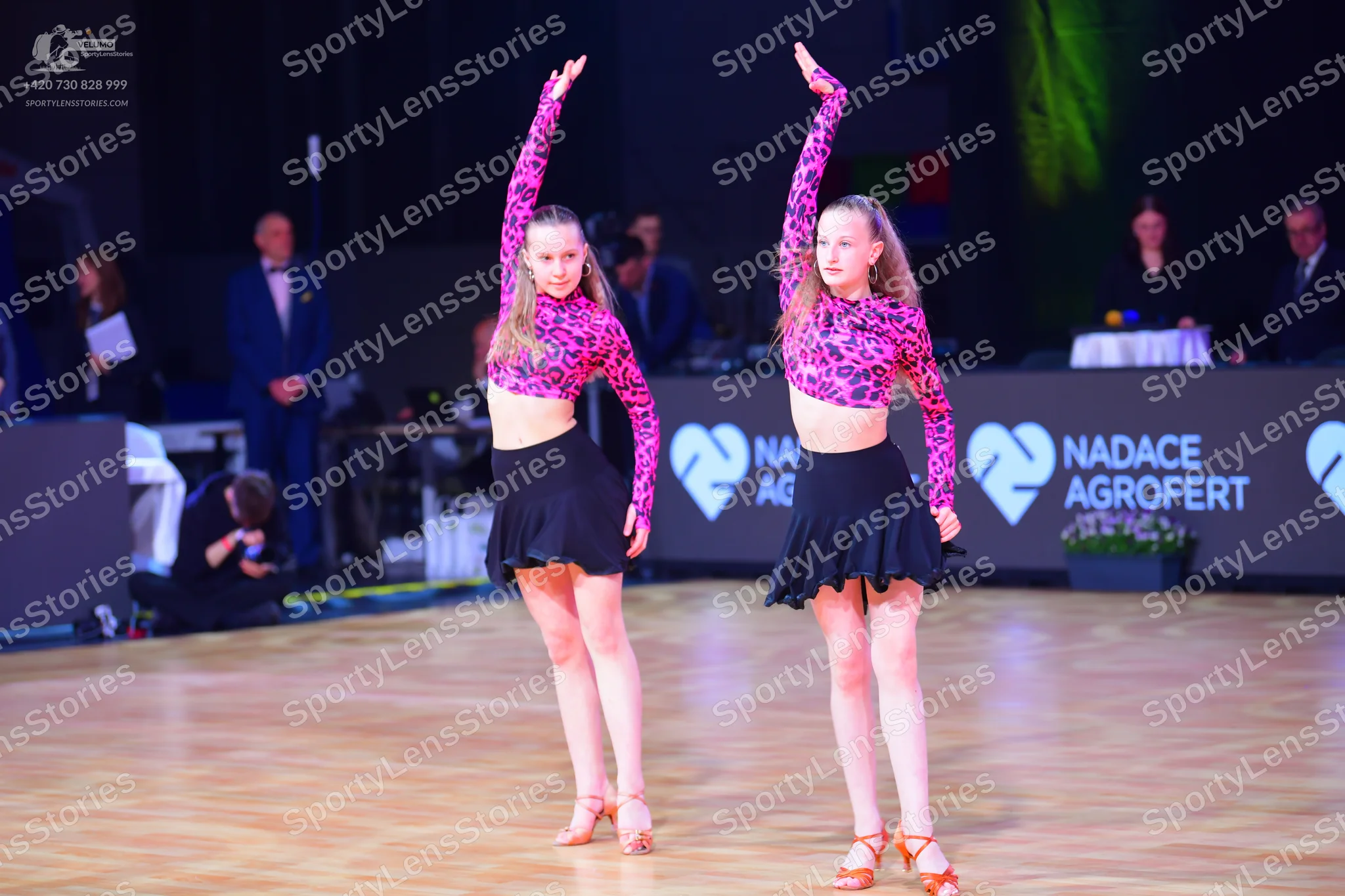 Dancesport competitor: Both female dancers are wearing matching outfits consisting of long-sleeved crop