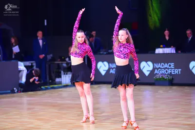 Dancesport competitor: Both female dancers are wearing matching outfits consisting of long-sleeved crop