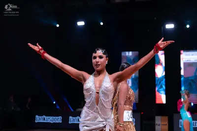 Dancesport competitor: Main female dancer: white/silver latin dress with a deep V-neckline, featuring b