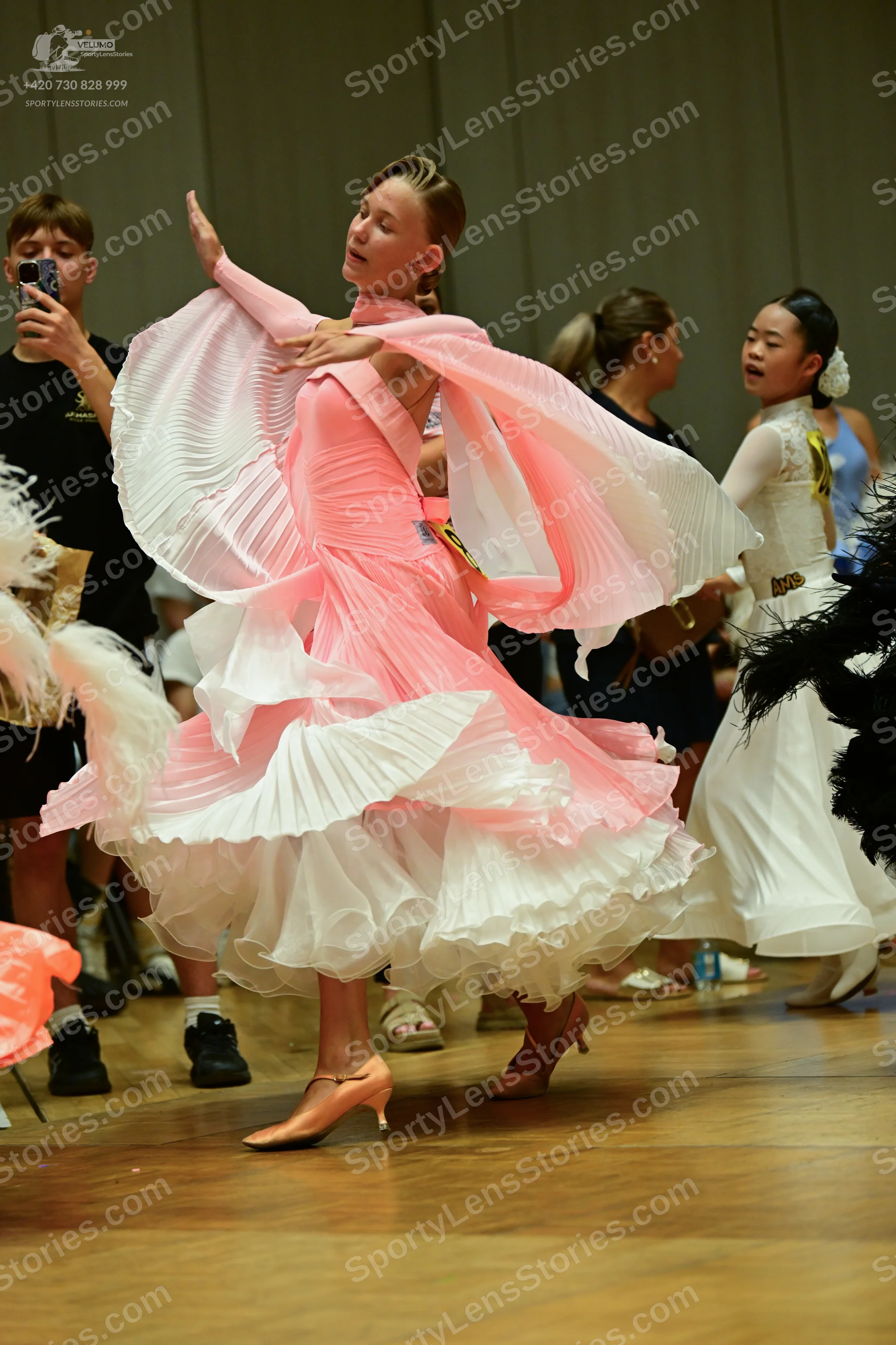 Dancesport competitor: **  She is wearing a voluminous, pale pink (almost white) pleated skirt
