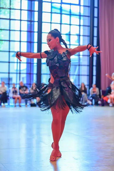 Dancesport competitor: Female dancer: black latin dress with a sequined bodice and a fringed skirt, wea