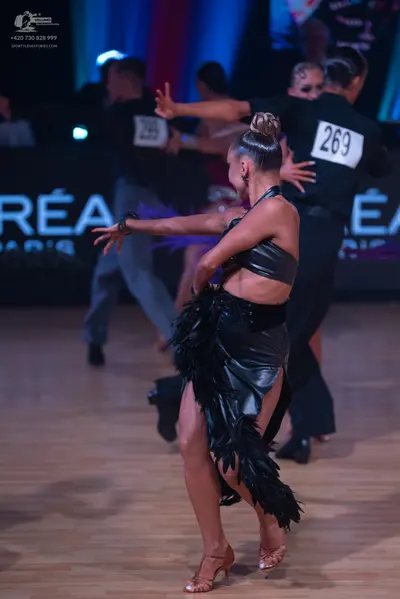 Dancesport competitor: Female dancer in foreground: black Latin dress with a satin-like bodice and a sk