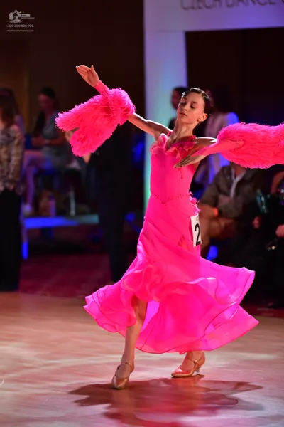 Dancesport competitor: Female dancer: bright pink ballroom dress with a voluminous, layered skirt and l