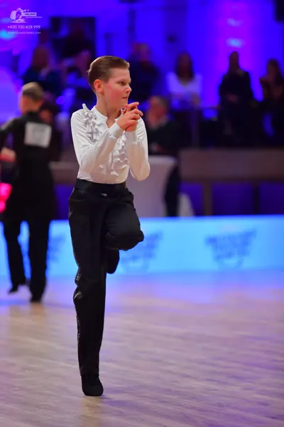 Dancesport competitor: Male dancer in foreground: white long-sleeved shirt with silver sequin embellish