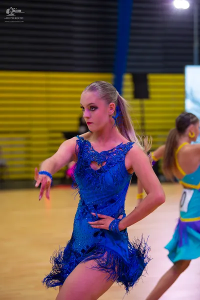 Dancesport competitor: ** Bright Blue, Fitted Latin Dress
*   **Fabric:** Primarily satin with a heavy,