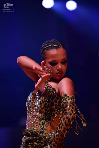 Dancesport competitor: Female dancer: leopard print Latin dress with sequin embellishments, featuring a