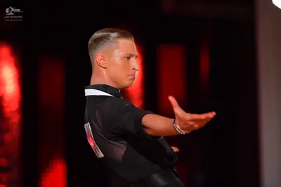 Dancesport competitor: Male dancer: black short-sleeved shirt with a white collar, black trousers, and 