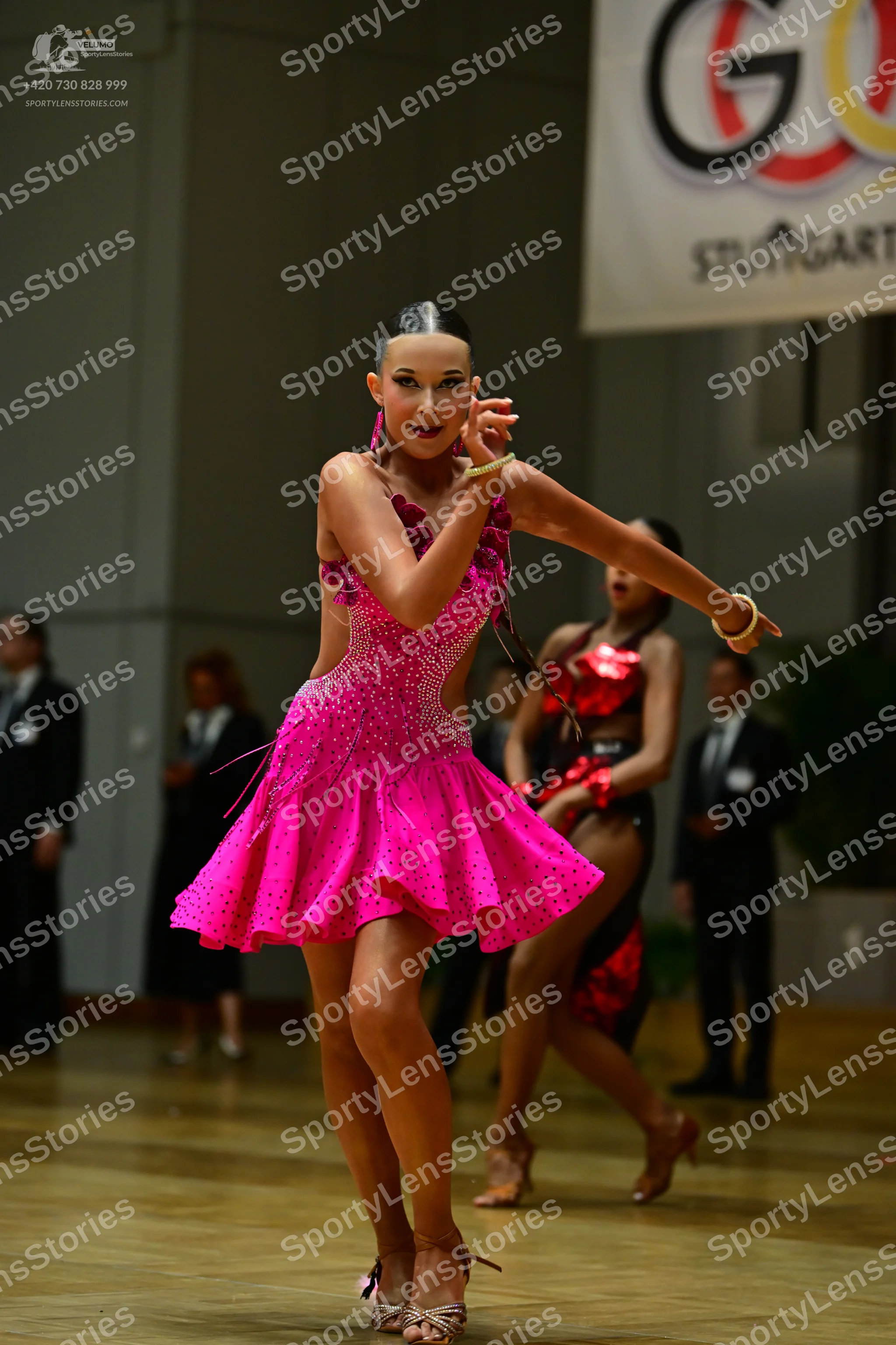 Dancesport competitor: Female dancer: bright pink latin dress covered in sequins with a flared skirt an