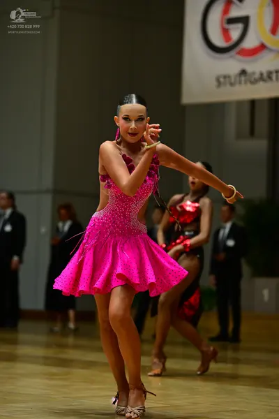Dancesport competitor: Female dancer: bright pink latin dress covered in sequins with a flared skirt an