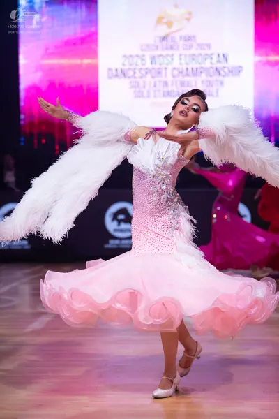 Dancesport competitor: Female dancer in foreground: light pink ballroom dress with a sequined bodice an