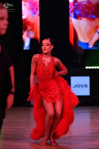 Dancesport competitor: Female dancer: red Latin dress with red sequins and fringe, matching red wristba