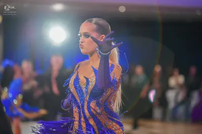 Dancesport competitor: Female dancer: blue and gold sequined Latin dance dress with long blue gloves