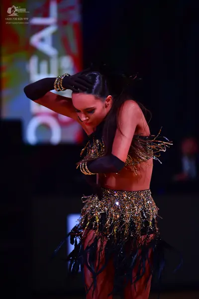 Dancesport competitor: Female dancer: black and gold latin costume with sequin/beaded patterns and long