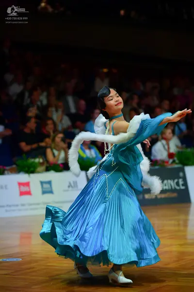 Dancesport competitor: Female dancer: teal ballroom gown made of a shiny, satin-like fabric with vertic
