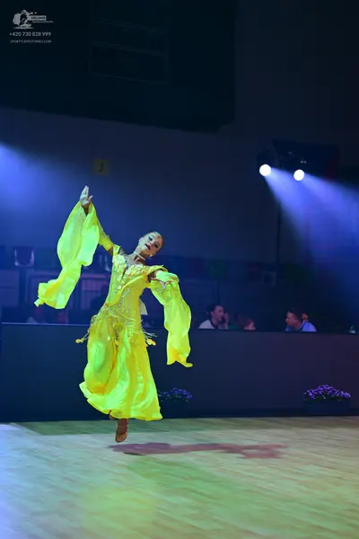 Dancesport competitor: Female dancer: bright yellow long ballroom dress with flowing bell sleeves and i
