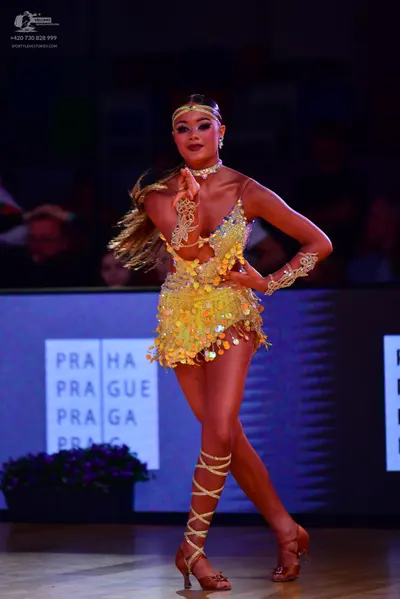 Dancesport competitor: Female dancer: yellow sequined Latin dance costume with a halter neck, cutout wa