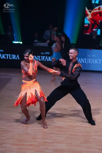 Dancesport competitor: Female dancer: orange and yellow Latin dance dress with flame-like layered fabri