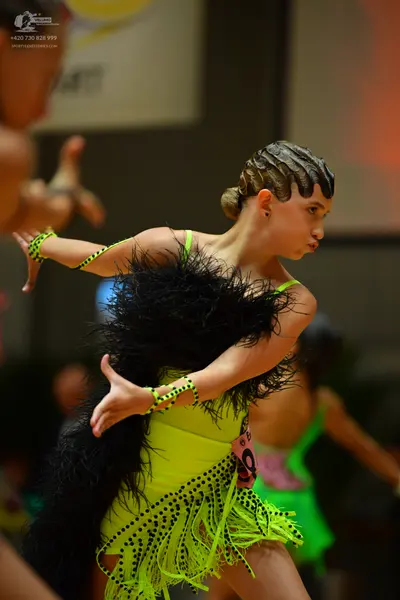 Dancesport competitor: Main dancer: Neon green Latin dance dress with black polka dot pattern on the bo