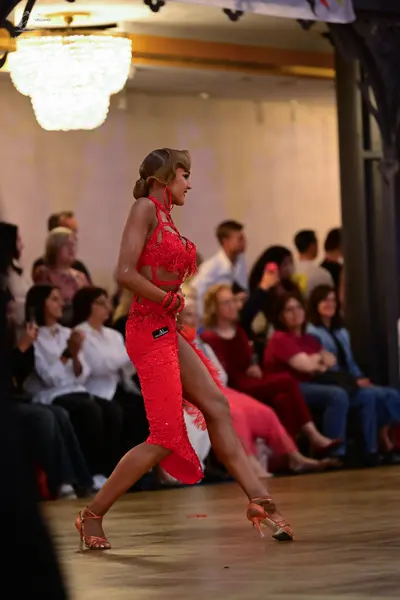 Dancesport competitor: Female dancer: red latin dress with sequins and a high slit