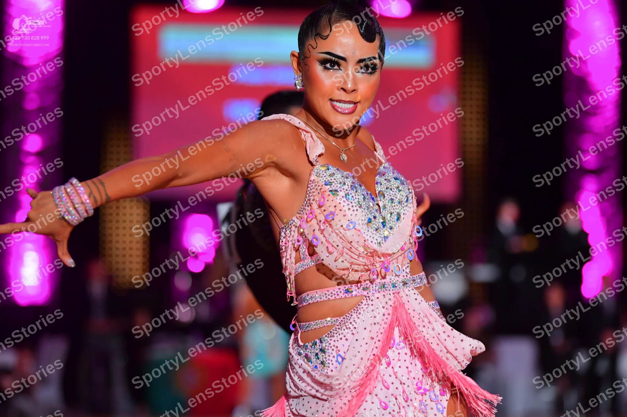 Dancesport competitor: Female dancer: light pink Latin dress with extensive rhinestone embellishments, 