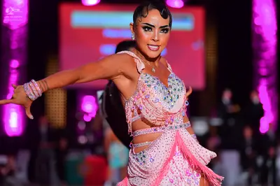 Dancesport competitor: Female dancer: light pink Latin dress with extensive rhinestone embellishments, 
