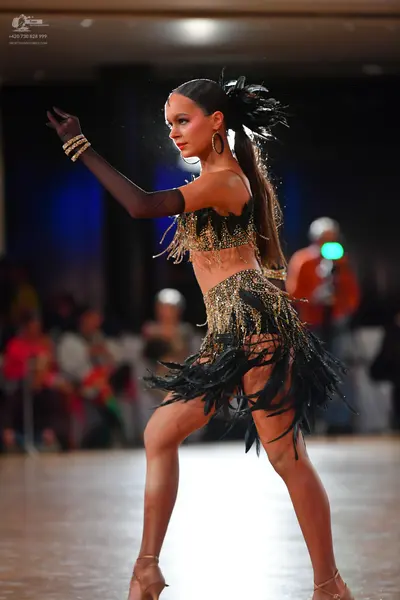 Dancesport competitor: Female dancer: black and gold latin costume consisting of a sequined crop top wi