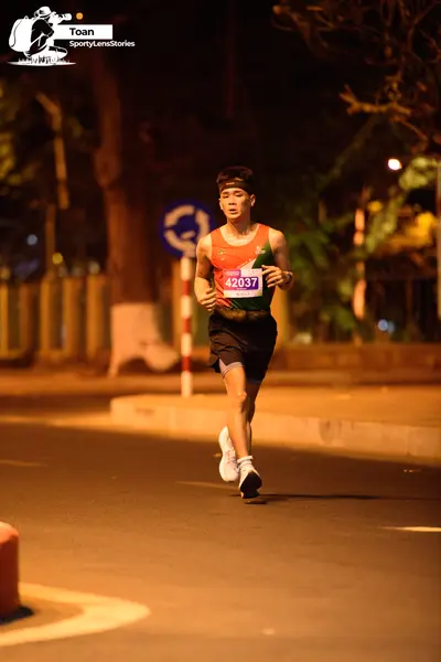 Marathon runner #42037: Runner 1: green, red and white tank top, black shorts, white shoes