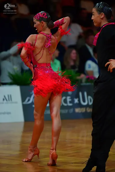 Dancesport competitor: Female dancer: red sequined Latin dance dress with fringe and a matching headban