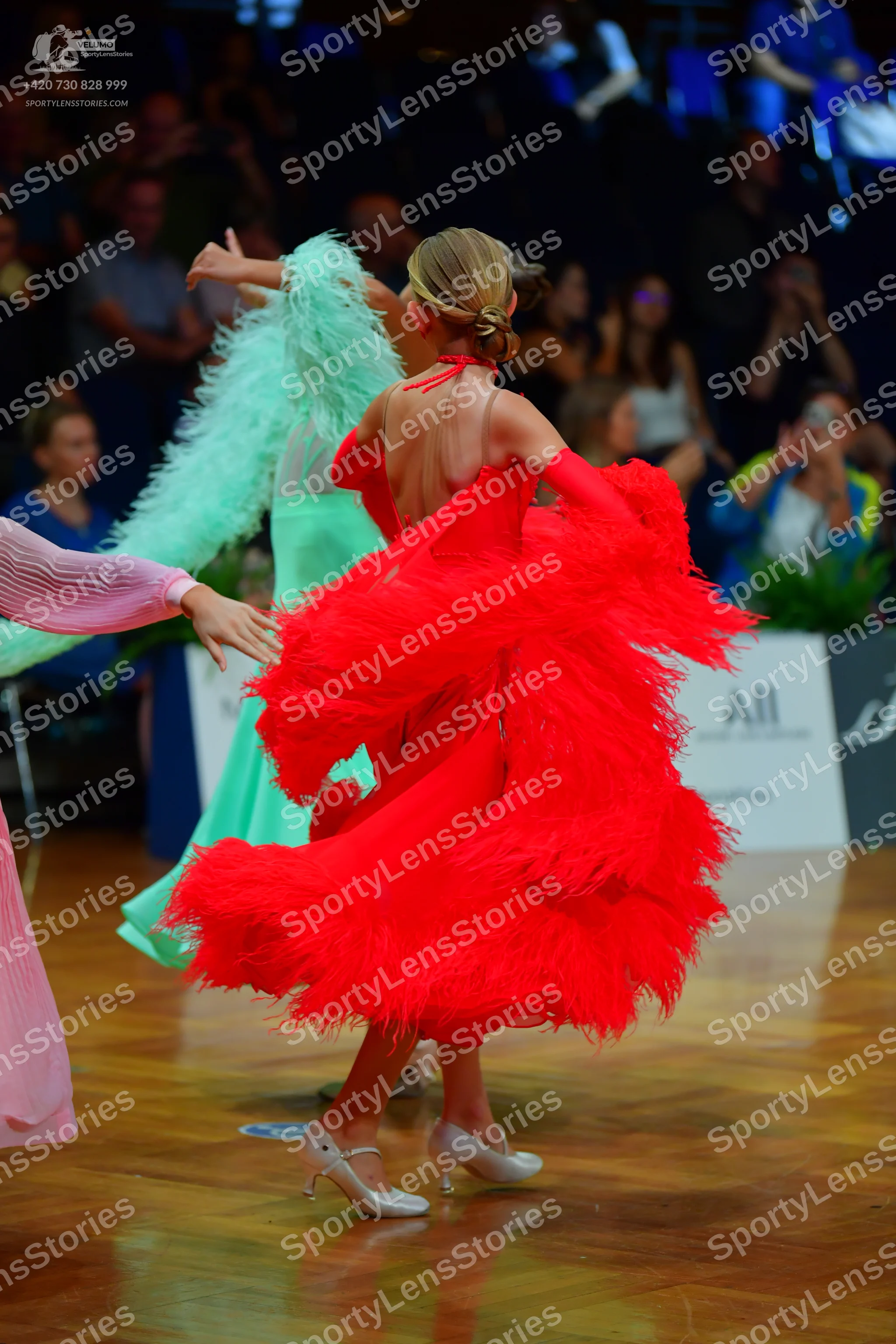 Dancesport competitor: Female dancer 1: red Latin dress with voluminous, feathery fringe and a backless
