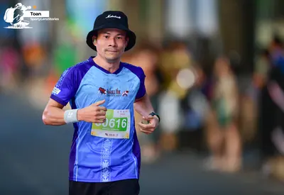 Marathon runner #0616: Runner 1: blue and purple short-sleeved jersey, black shorts, black bucket hat, 