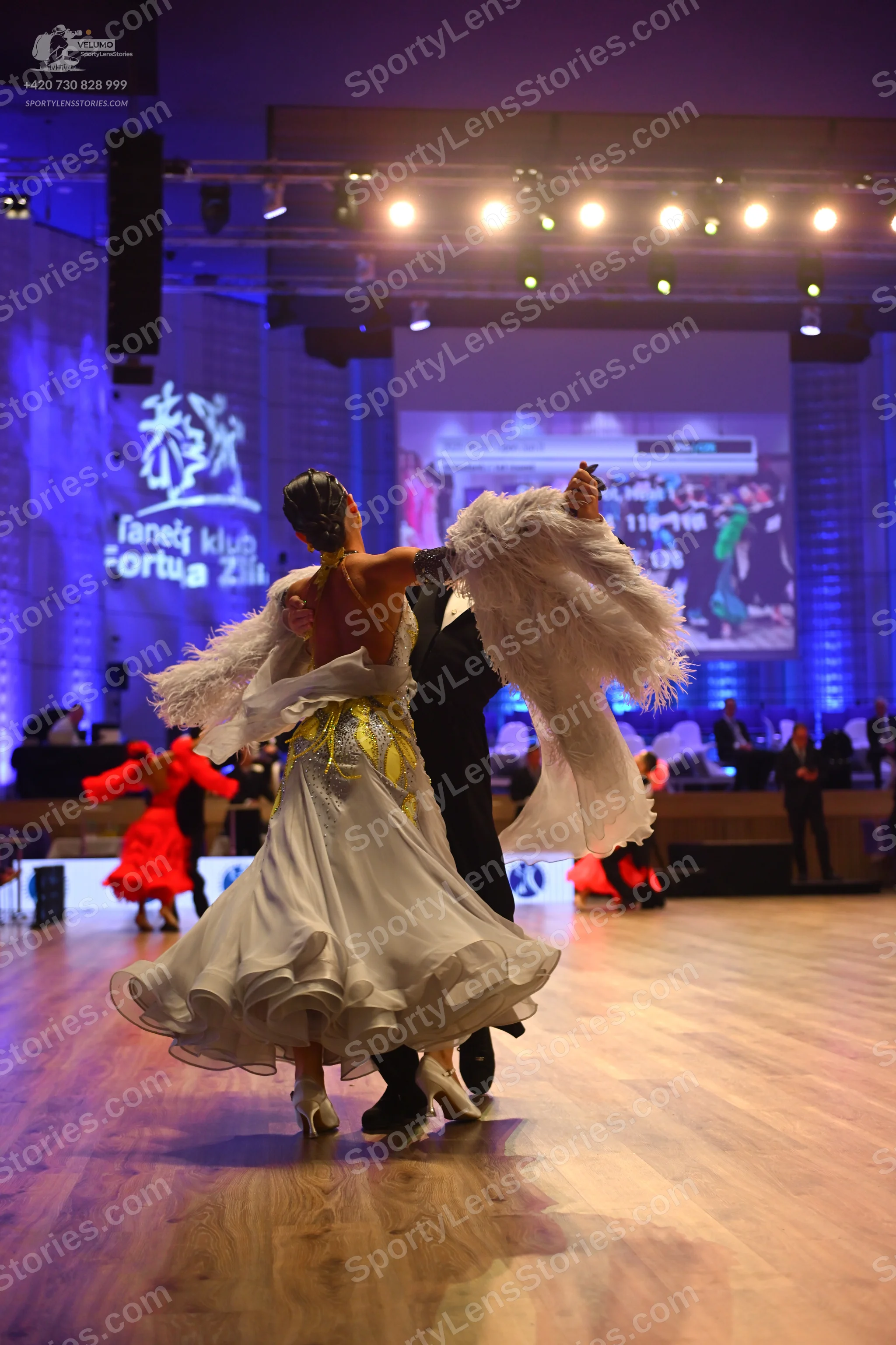 Dancesport competitor: Female dancer: white ballgown with a voluminous, ruffled skirt and yellow/gold s