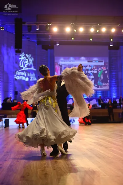 Dancesport competitor: Female dancer: white ballgown with a voluminous, ruffled skirt and yellow/gold s