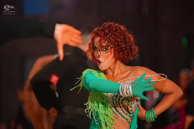 Dancesport competitor: Female dancer: bright green Latin dress with long sleeves, green fringe, and sil