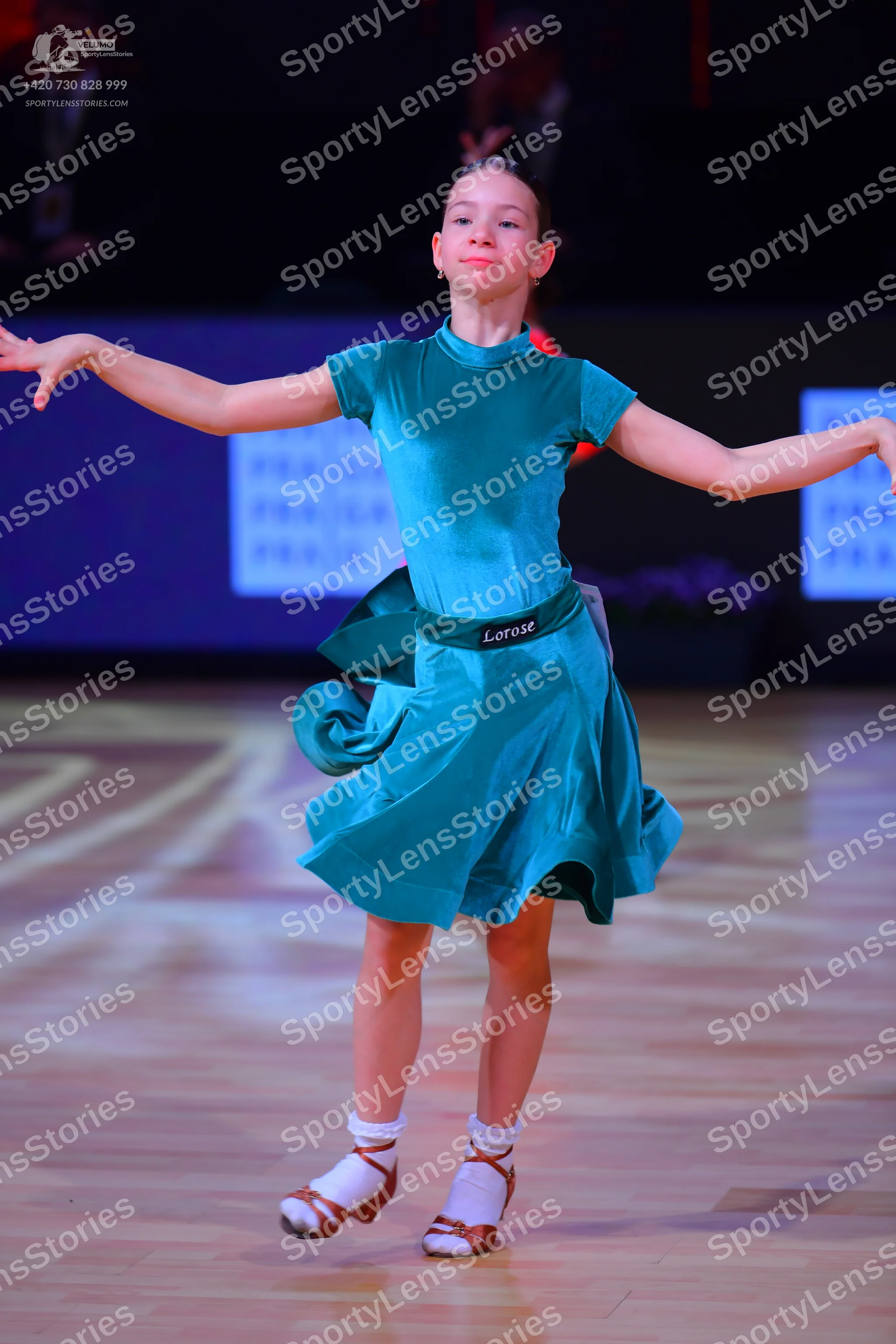 Dancesport competitor: Female dancer: teal satin-like dress with short sleeves, a high neckline, and a