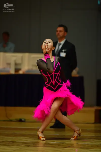Dancesport competitor: Female dancer: black and bright pink latin dress with a feathery pink skirt and 