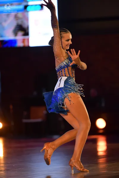 Dancesport competitor: Female dancer: blue latin dress with sequins, fringe, and sheer long sleeves