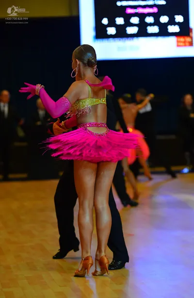 Dancesport competitor: Female dancer: bright pink Latin dance dress with a gold sequined bodice, pink f
