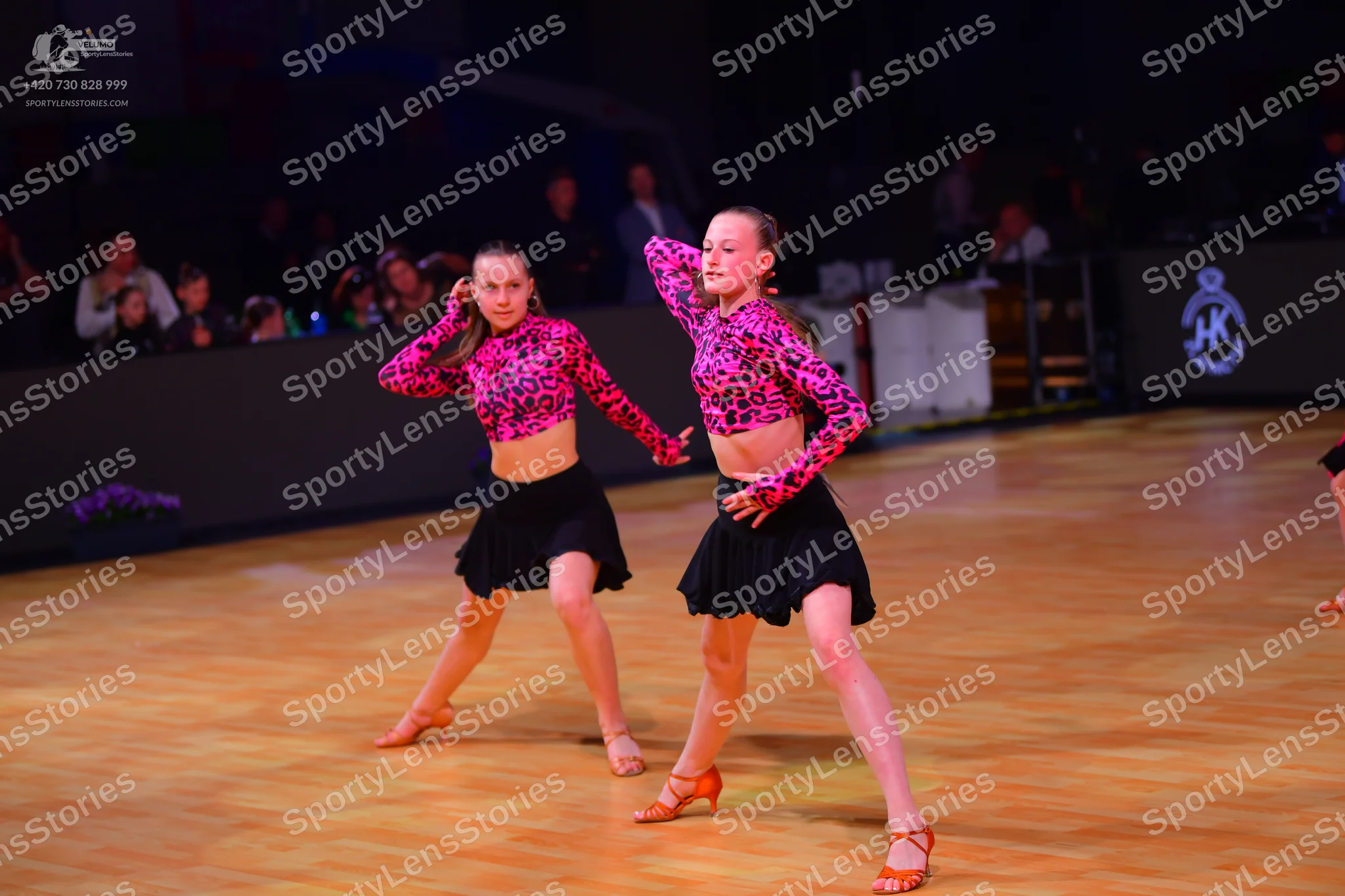 Dancesport competitor: Female dancers: matching pink and black leopard print long-sleeved crop tops and