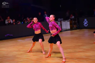 Dancesport competitor: Female dancers: matching pink and black leopard print long-sleeved crop tops and