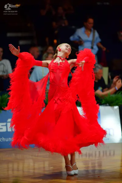 Dancesport competitor: Female dancer: red latin dress with feathery/fringed skirt and sleeves, sequin b