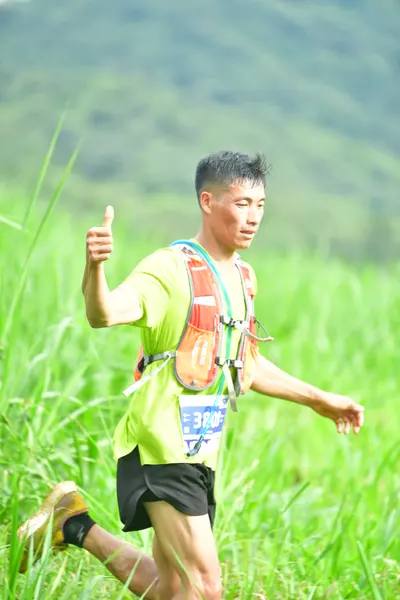 Marathon runner #306: Runner 1: lime green shirt, black shorts, tan shoes, hydration vest