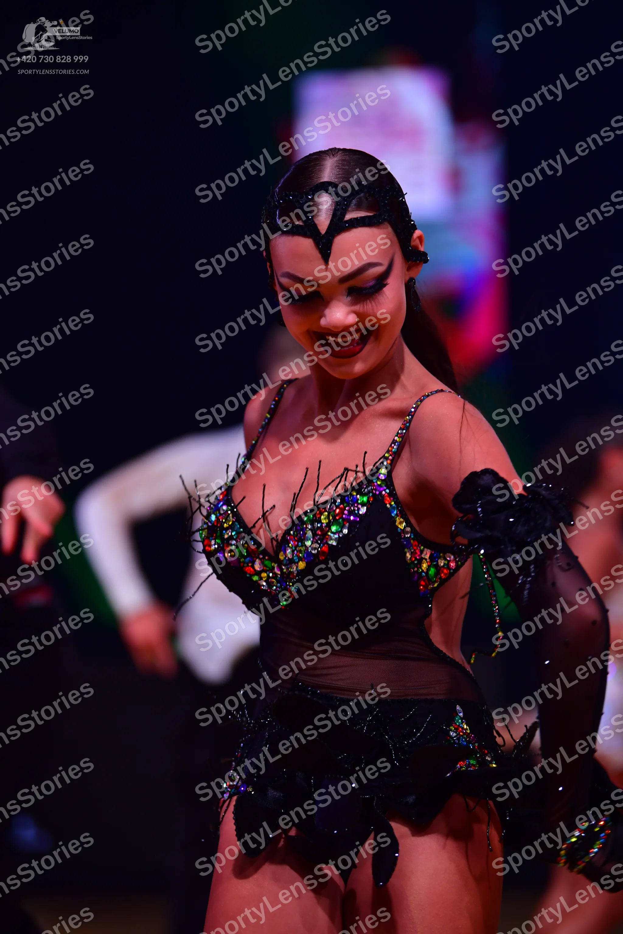 Dancesport competitor: Female dancer: black Latin costume with colorful sequins (green, blue, gold), sh