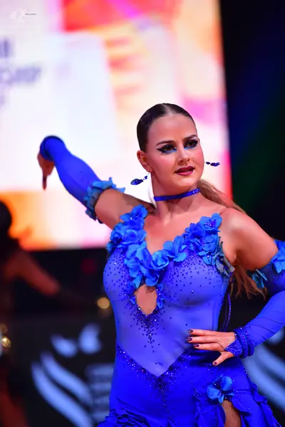 Dancesport competitor: Female dancer: bright blue Latin dance dress with 3D floral appliqués, rhineston