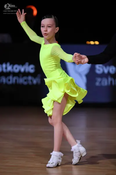 Dancesport competitor: Female dancer: neon yellow long-sleeved Latin dress with a ruffled skirt and whi